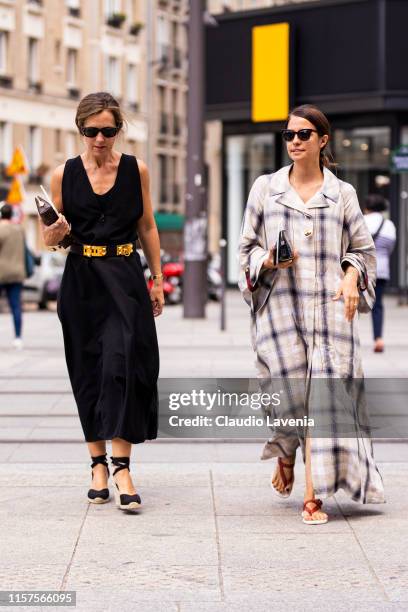 Guests, wearing a black dress, gold belt and black espadrilles , and long checked dress and red sandals , are seen outside Jil Sander fashion show on...