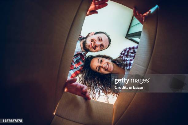 glückliches junges paar schaut in die box - ursprung stock-fotos und bilder
