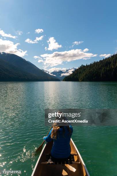 woman paddling canoe in lake against sky - whistler stock pictures, royalty-free photos & images