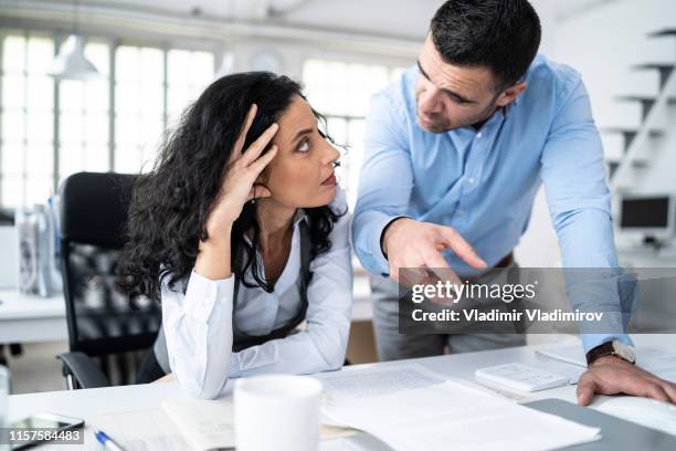 colleghi seduti sul posto di lavoro e che discutono dei problemi - irritazione foto e immagini stock