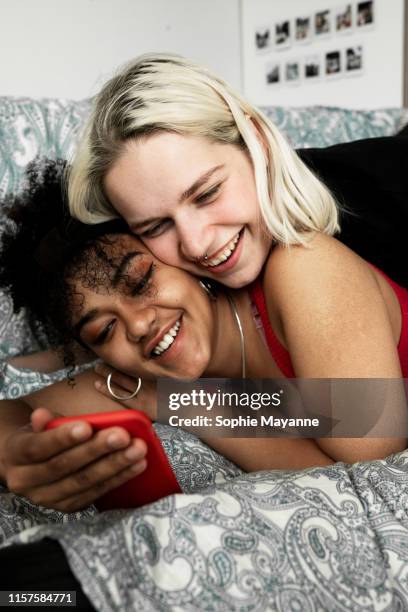 LGBT couple lying together laughing at a mobile phone