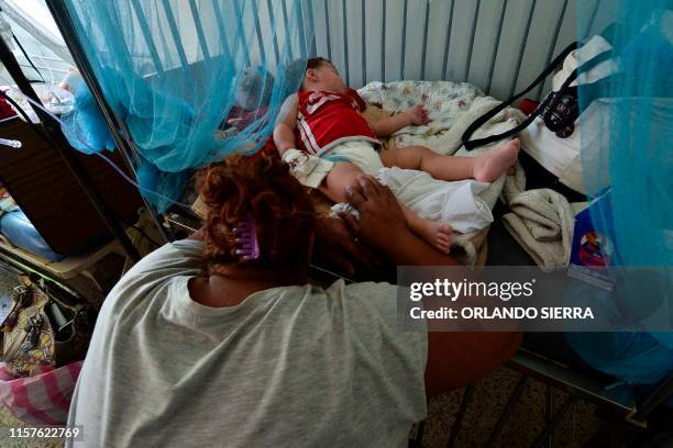 Woman rests next to his son infected with dengue, which vector is the Aedes aegypti, is assisted in the Roberto Suazo Cordova Hospital, in La Paz...
