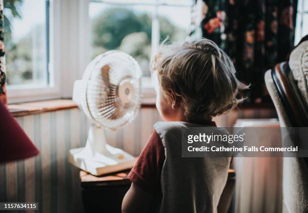 little boy looking at a fan - heat temperature 個照片及圖片檔