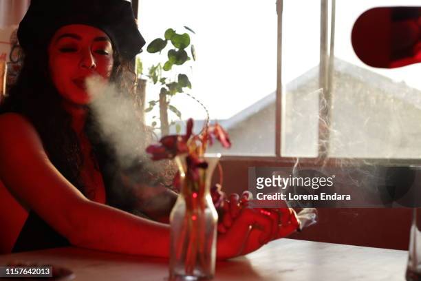 young woman smoking joint in her living room - smoking weed stock-fotos und bilder