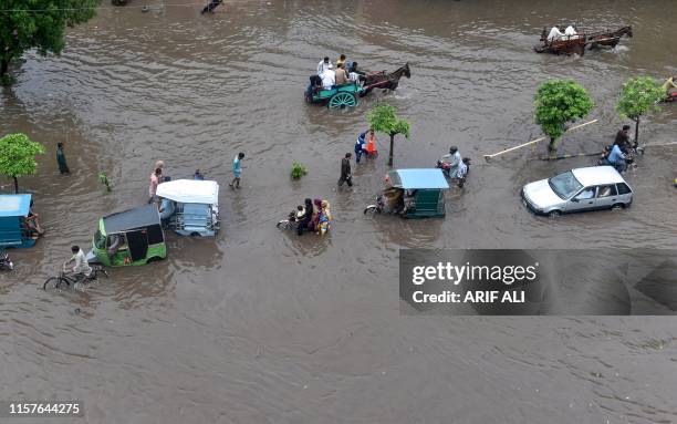 Commuters drive through a flooded street during heavy monsoon rains in Lahore on July 25, 2019.