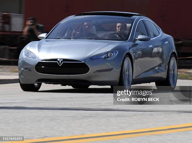 Tesla Motors Chairman and CEO Elon Musk and chief designer Franz von Holzhausen drive the new Tesla Model S all-electric sedan out into the street as...