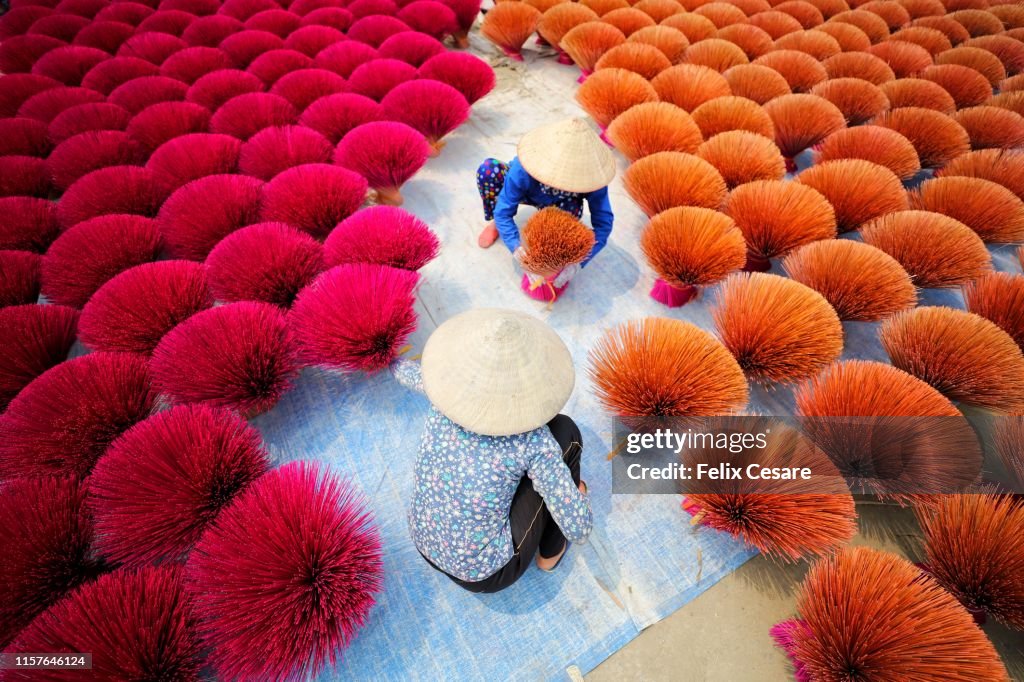 Two Vietnamese women surrounded by bouquets of incense sticks