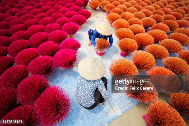 two vietnamese women surrounded by bouquets of incense sticks - vietnam stock pictures, royalty-free photos & images