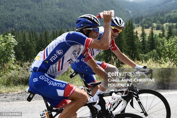 France's Thibaut Pinot , past his teammate France's Matthieu Ladagnous, pours water on his head as a heat wave hit Western Europe during the...