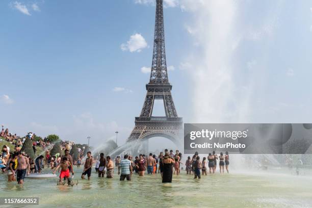 Many people of all ages bathe in the Fountain of the Trocadero to cool down with the Eiffel Tower in the background as a landscape as Paris and...