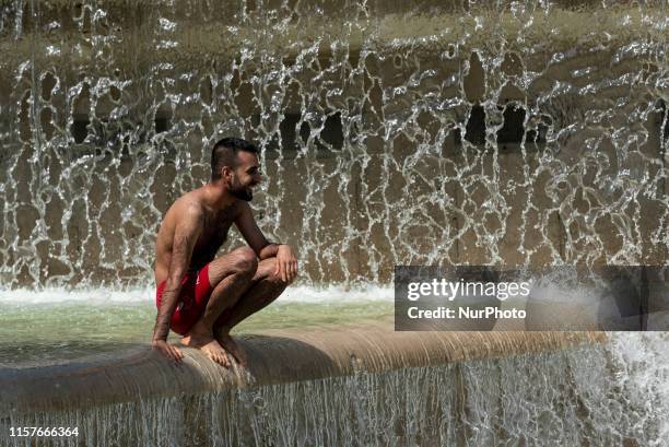 Man in a bathing suit crouches down by the Trocadero fountain to cool down as Paris and France as a whole go through their second heat wave since the...