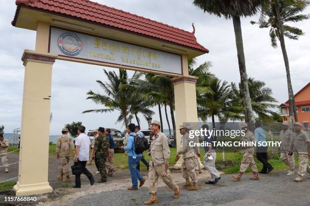 Cambodian navy personnel walk with journalists during a government organised media tour to the Ream naval base in Preah Sihanouk province on July 26,...