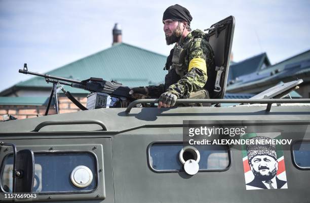Chechen special force trooper sits atop an APC decorated with a portrait of former Chechen president Akhmad Kadyrov, the father of the current...