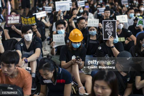 Demonstrator wearing a hard hat looks at a smartphone during a protest at the Hong Kong International Airport in Hong Kong, China, on Friday, July...
