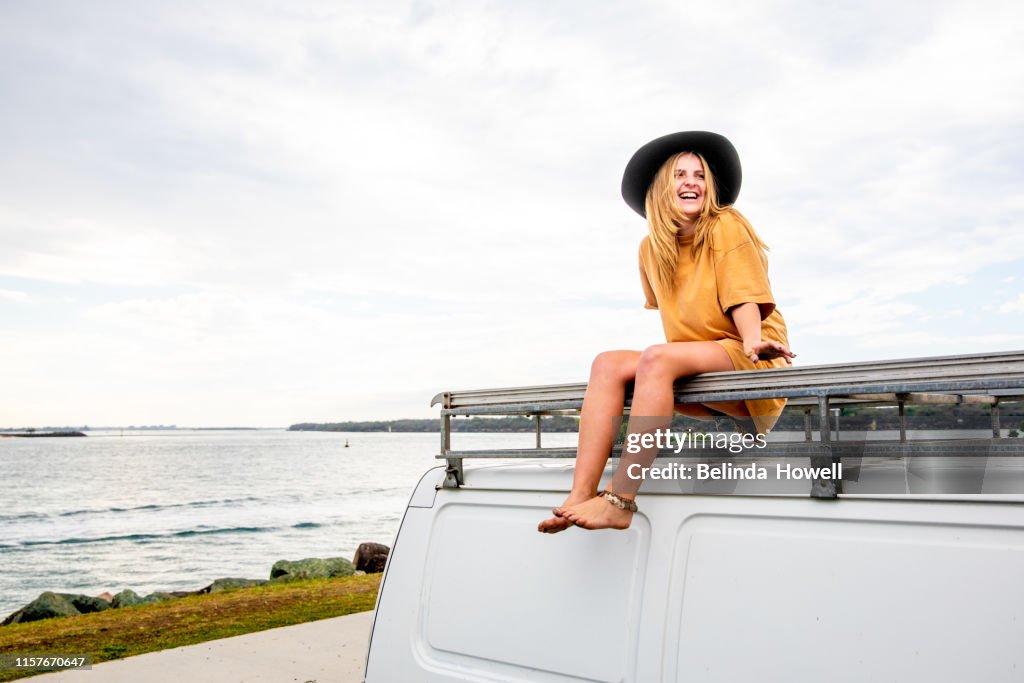 Woman travelling solo with her van and her surfboard by the Australian sea