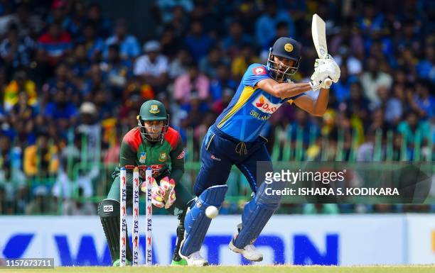 Sri Lankan captain Dimuth Karunaratne plays a shot as Bangladesh Wicketkeeper Mushfiqur Rahim looks on during the first One Day International cricket...