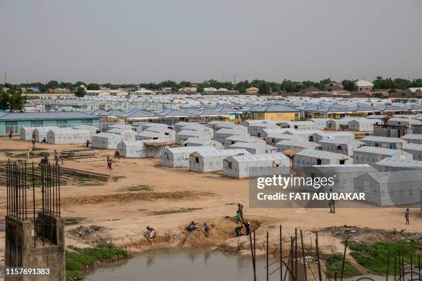 People stand on July 26, 2019 at the unfinished Mohammed Goni Stadium in Maiduguri where internally displaced persons from other congested IDP camps...