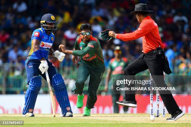 Bangladeshi cricketer Mosaddek Hossain tries to stop the ball as Sri Lankan cricketer Kusal Perera looks on during the first One Day International...