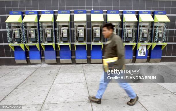 Peruvian passes in front of public telephone booths of the Spanish transnational Telefonica, in Lima on June 10, 2004. The government of Peru decided...