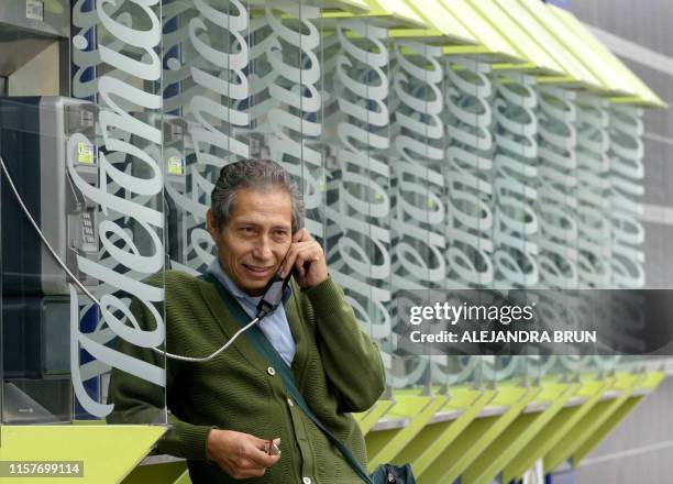 Peruvian speaks from a public telephone supplied by the Spanish transnational Telefonica, in Lima on June 10, 2004. The government of Peru decided...