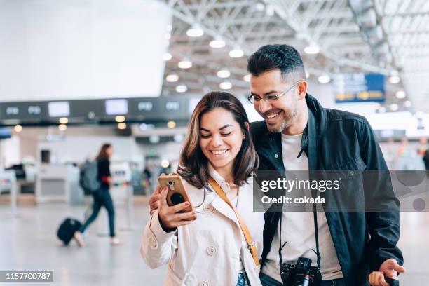 couple using smartphone at the airport - couple airport stock pictures, royalty-free photos & images