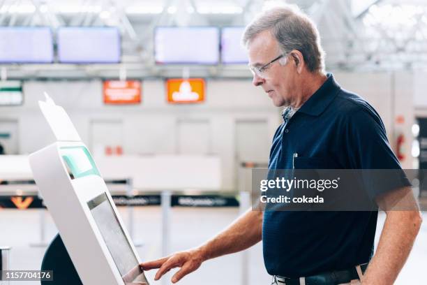 senior men using check in totem at the airport - totem pole stock pictures, royalty-free photos & images