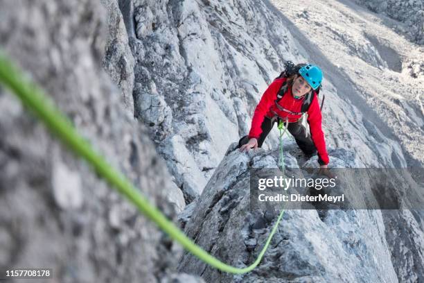 rotsklimmen in de alpen-jonge vrouw klimmen in de alpen - team climbing up to mountain top stockfoto's en -beelden