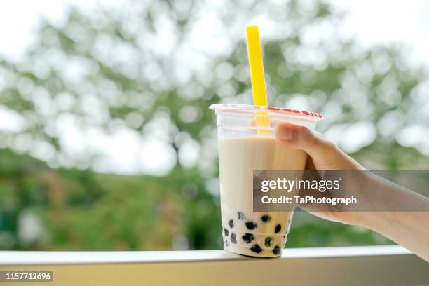 human hand holding a cup of iced cold bubble tea with milk and tapioca pearls - milk tea cup stock pictures, royalty-free photos & images