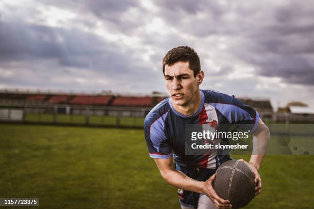 determined sportsman running with ball on rugby field. - rugby league stock pictures, royalty-free photos & images