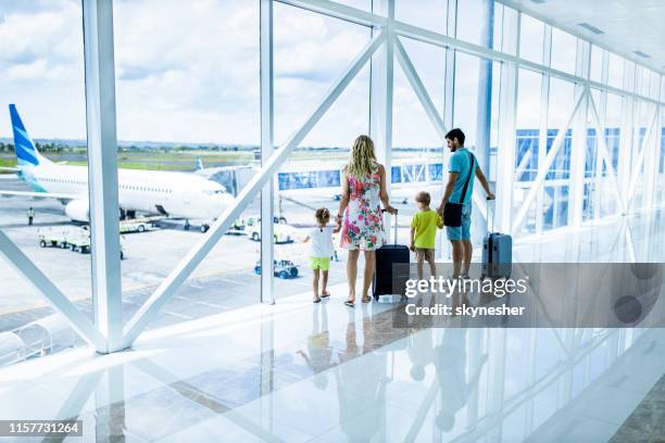 back view of a family looking through window at airport hallway. - indonesia family imagens e fotografias de stock