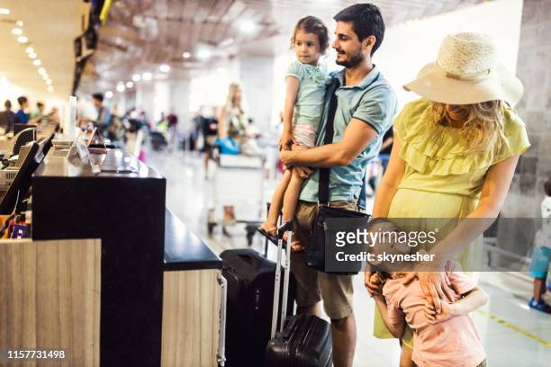 joven familia revisando sus suplicaciones en la terminal del aeropuerto. - family at airport fotografías e imágenes de stock