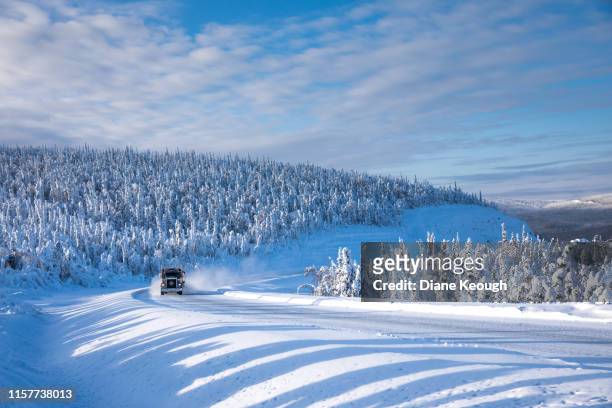 large truck with load on the trailer moving at speed along the icy, snowy, tree lined dalton highway in the alsakan wilderness. the snow sprays from the road outwards from the side of the truck. - truck side view stock pictures, royalty-free photos & images
