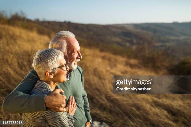 omarmd senior paar genieten in de herfst dag op een veld. - pensioen thema stockfoto's en -beelden