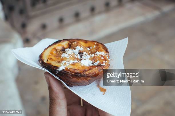 hand holding a traditional portuguese tart from pasteis de belem in lisbon, portugal - pastry imagens e fotografias de stock