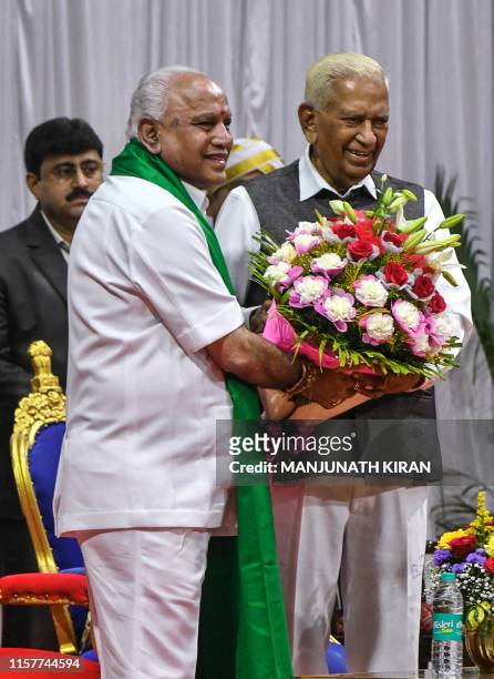 Governor of Karnataka, Vaju Bhai Valla , and senior leader of Bharatiya Janata Party , B.S. Yediyurappa , hold flowers during Yediyurappa's swearing...