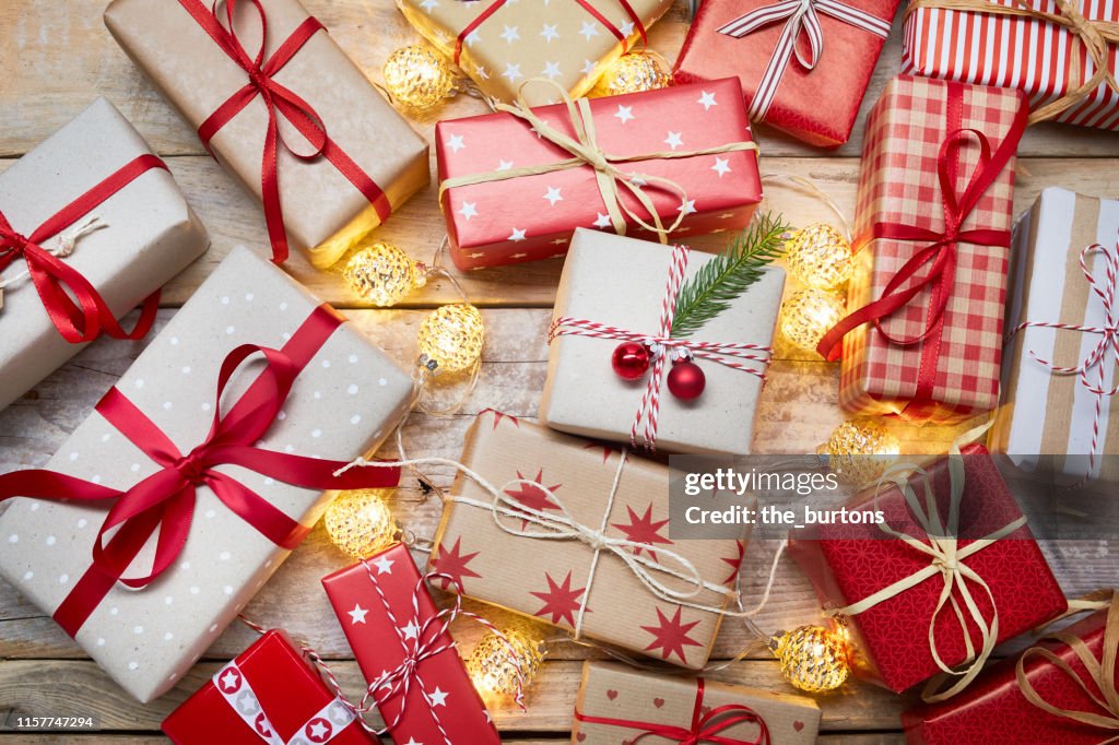 High angle view of a lot of wrapped Christmas presents and Christmas lights on wooden table