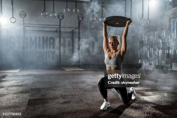 donna atletica che si allena con dischi di peso in palestra. - affondo foto e immagini stock