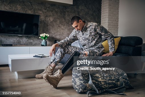 Depressed soldier with amputee leg sitting in the living room Depressed soldier with amputee leg sitting in the living room