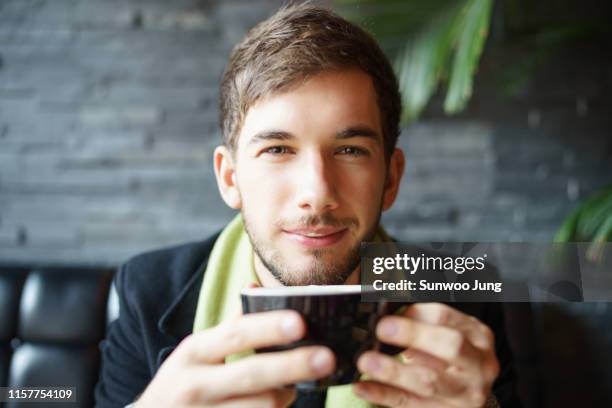 portrait of young man in cafe holding mug - staring stock pictures, royalty-free photos & images