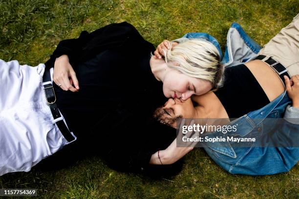 lgbt couple lying in the grass kissing - embrasser sur la bouche photos et images de collection