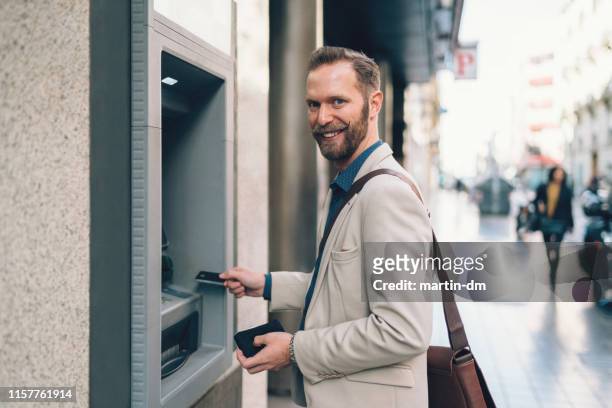 businessman withdrawing money - man atm smile stock pictures, royalty-free photos & images