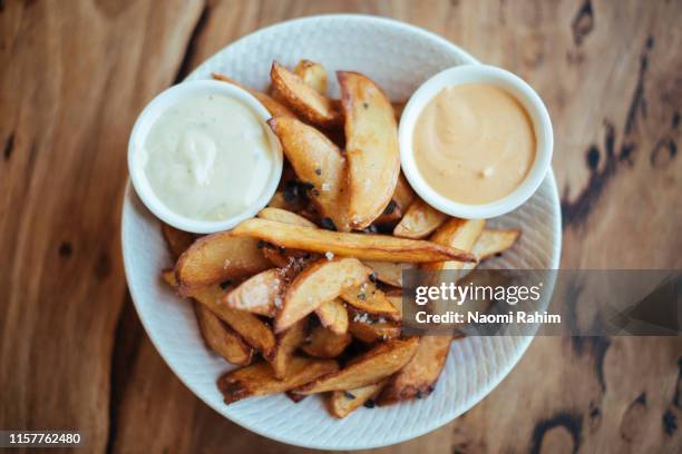 Gourmet Potato Wedges Served With Black Sea Salt Aioli In A White Bowl Shot Directly Above, Stock-Foto