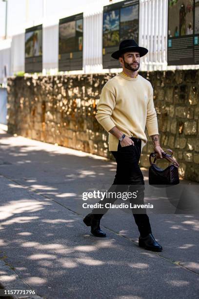 Pelayo Diaz, wearing a yellow jumper, black pants, black boots, brown bag and black hat, is seen outside Loewe fashion show on Day 5 during the Paris...
