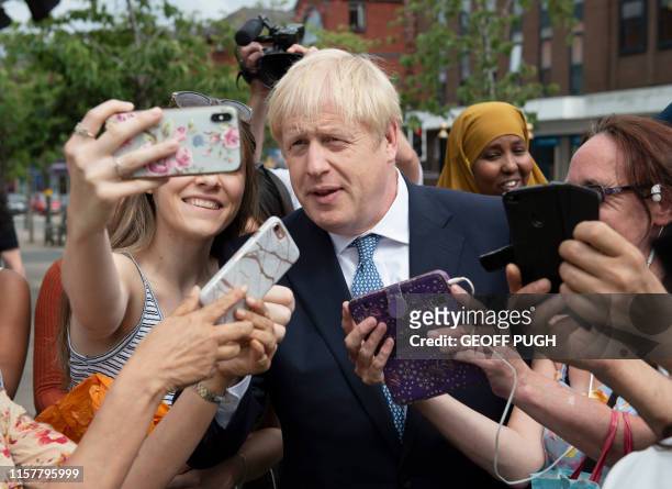 Britain's Prime Minister Boris Johnson poses for selfie photographs with members of the public as he takes a walkabout with Britain's Home Secretary...