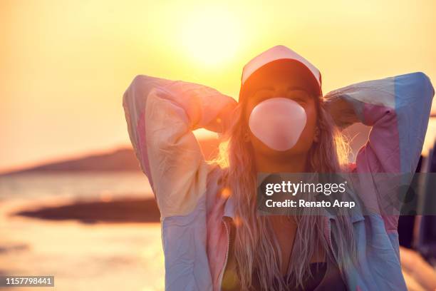 hipster teenage girl blowing pink bubble gum at sunset - bubble gum stock pictures, royalty-free photos & images