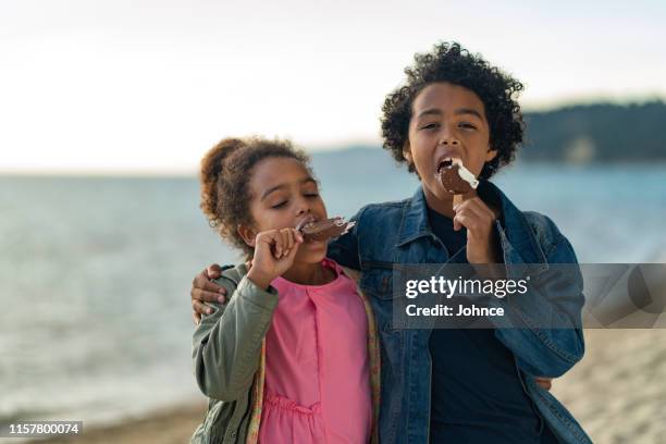 kinder genießen eis am strand - boy and girl eating ice cream stock-fotos und bilder