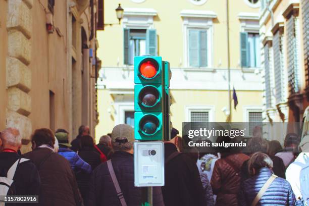 red light at a traffic light on a street full of tourists - road signal stock pictures, royalty-free photos & images