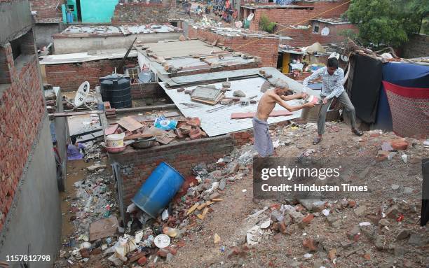 People residing in Girdharipura slum retrieve their belongings from inundated houses during rains that have been intermittently on for more than...
