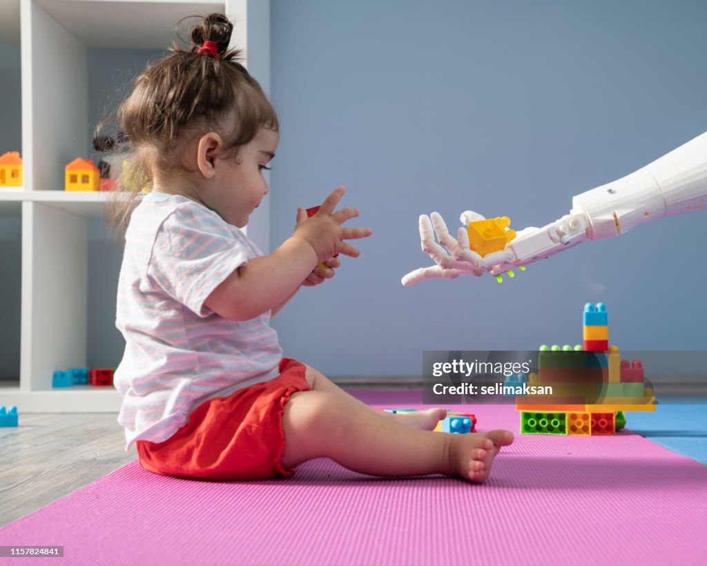 Baby meisje en robot spelen met speelgoed blokken