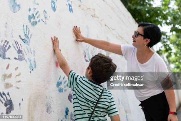 mother and son painting wall with hands - paint handprint stock pictures, royalty-free photos & images